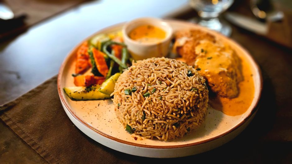 A sumptuous dinner plate featuring seasoned rice, chicken, and colorful vegetables.